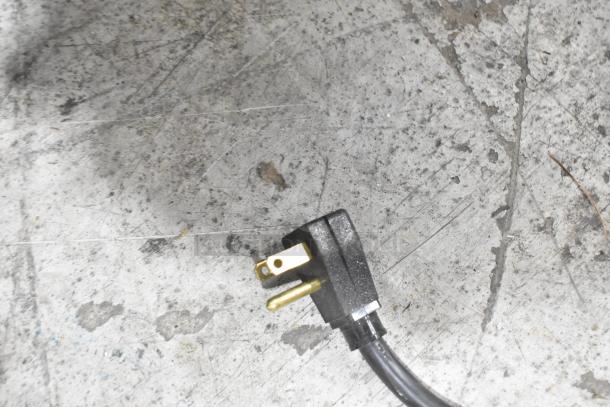 Electrical plug for a 2020 True T-19F-HC commercial freezer. Black cord on a textured surface.