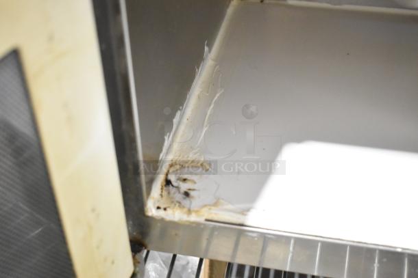 Close-up of interior damage in a Menumaster MDC182 stainless steel commercial countertop microwave oven. Visible wear and burn marks.