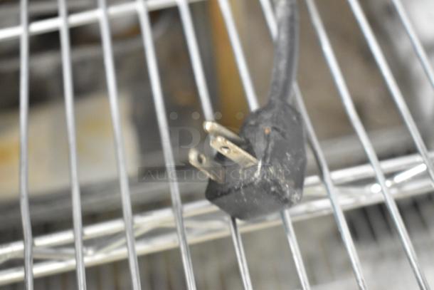 Plug of Menumaster MDC182 stainless steel commercial microwave, 208/230 volts, 1 phase, shown on a metal grid shelf.