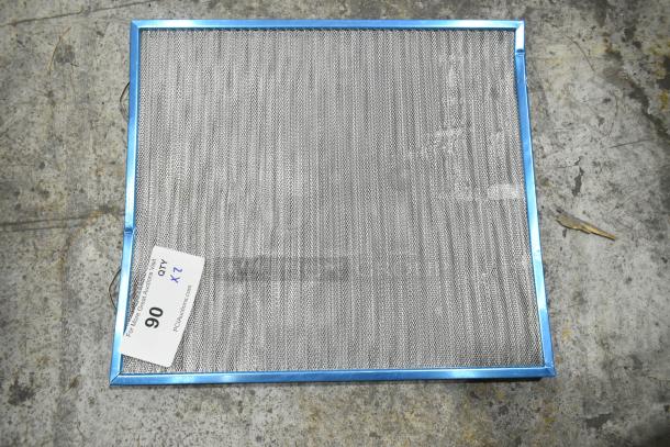Two metal filters with blue frames, number 90 tag indicating "2X" bid quantity, placed on a textured surface.