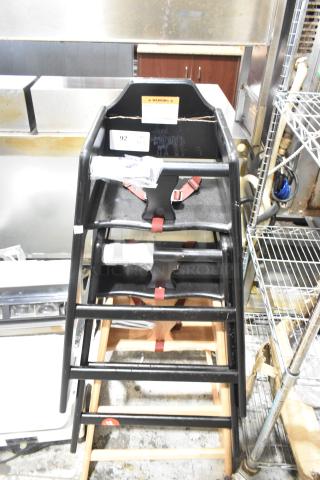 Three stacked wooden high chairs with black finish, red safety straps, and visible warning label. Auction item number 92.