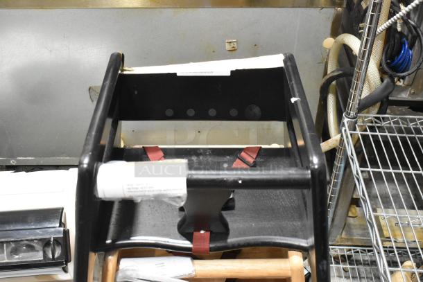 Three wooden high chairs, black finish, with red straps. Features minor wear. Appears sturdy and functional for use.