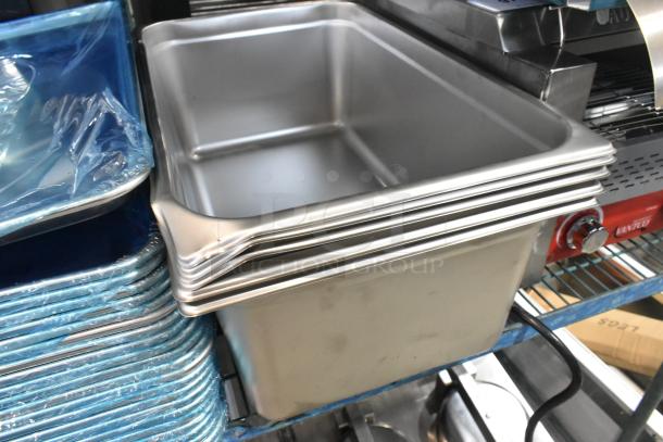 Stack of new stainless steel steam table pans and aluminum sheet pans, pristine condition, ready for auction.
