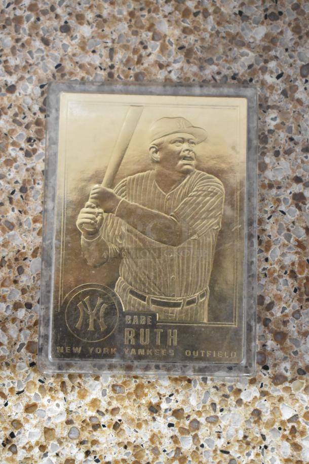 Gold-toned Babe Ruth baseball card featuring etched image and New York Yankees logo, in protective case.