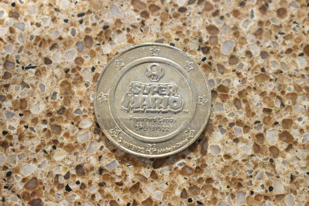 Super Mario coin by Frankford Candy, OPL 181022, collectible item with engraved stars and logos.