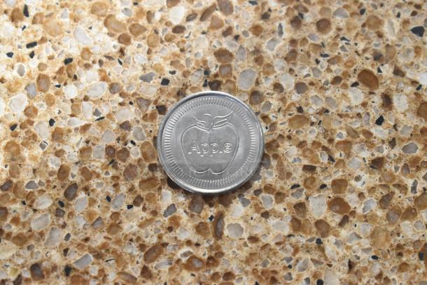 Silver coin with "Apple" and apple logo, part of 4-item set including $1 Cayman Islands notes and Super Mario coin.