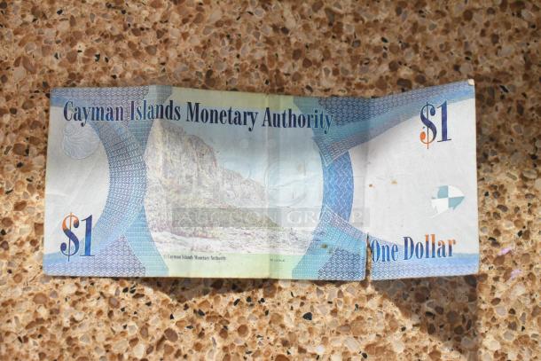 Two Cayman Islands $1 bills, featuring scenic design, worn condition, with "Cayman Islands Monetary Authority" text.
