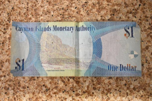 Cayman Islands $1 bill, showing landscape and "Cayman Islands Monetary Authority." Lightly worn, fine condition.