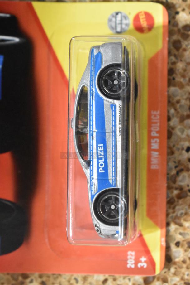 BMW M5 Polizei Matchbox car, new in packaging. Features blue and silver design, marked "MEX GERMANY." Mattel, 2022, age 3+.