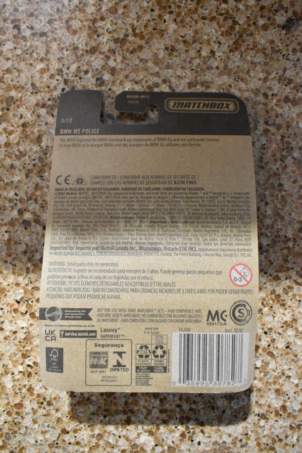 Matchbox BMW M5 Police car packaging, includes safety warnings, barcode, and manufacturer details. Made in Thailand.