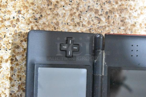 Close-up of black Nintendo DS showing the directional pad, slight wear visible near the hinge.