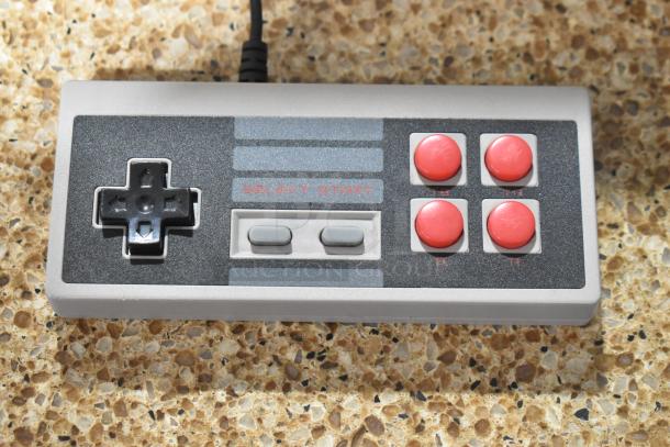 Coolbaby RS-41 game console controller with black d-pad, red buttons, and "Select Start" label, on stone surface.