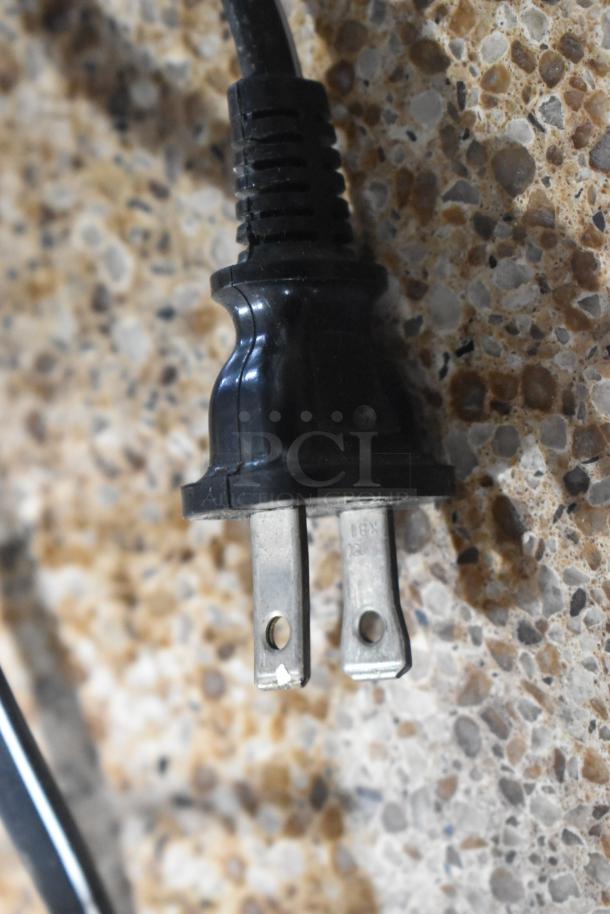 Close-up of a black power plug on a speckled surface.
