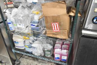 Two-tier shelf with Diversey Wiwax, Restroom Cleaner, and Scott Foam Skin Cleanser, plus box labeled 365714, 4/3/25.