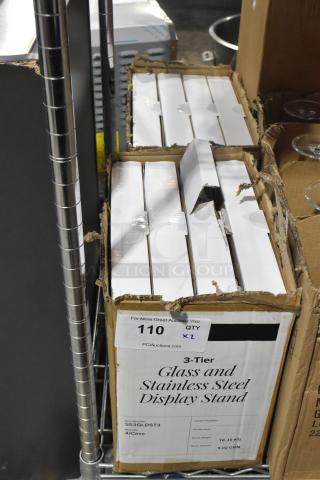 2 boxes of 4 Acopa 553GLDST3 3-tier glass/stainless steel display stands, new scratch and dent, boxed, quantity labels visible.
