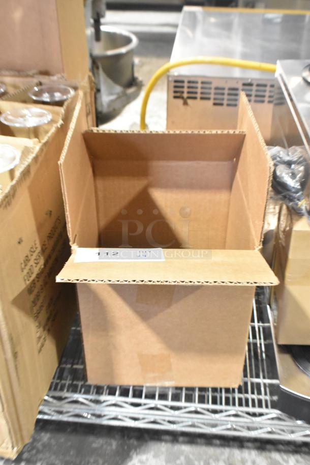 Lot of 4 commercial casters, brand new with minor scratches and dents, in open cardboard box on metal shelf.