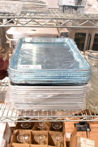 20 brand new items including 407BUNHALF aluminum bun pans and 1517 non-stick bread pans, sealed in plastic, on metal shelf.