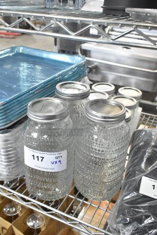 Brand new lot of 9 scratch and dent glass jars with textured finish, labeled "117 QTY VX9" for auction.
