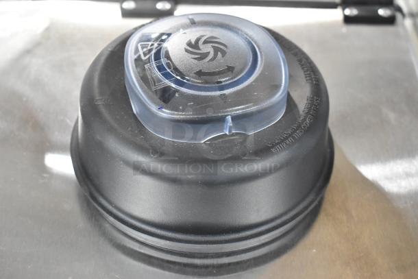 Black blender pitcher lid with clear center cap featuring arrow design, no visible scratches or dents.