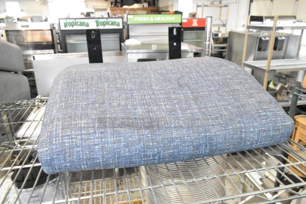 Blue fabric seat cushion, scratch and dent condition, on metal shelving. Ideal for seating, new with minor imperfections.
