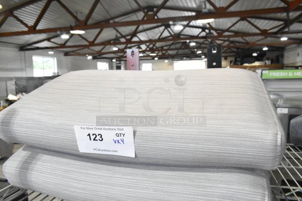 Four brand new scratch and dent seat cushions, light gray, striped texture, with auction label indicating quantity "QTY x4".