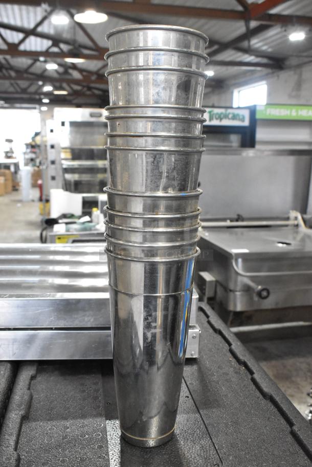 Lot of metal mixing cups stacked on industrial surface in good condition. Part of an auction lot with grease hood filters and bins.