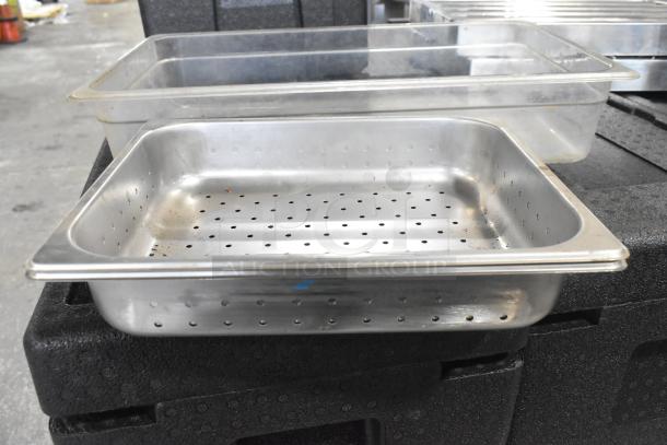 Lot of various metal kitchen items including perforated stainless steel pans and clear drop-in bins, all in used condition.