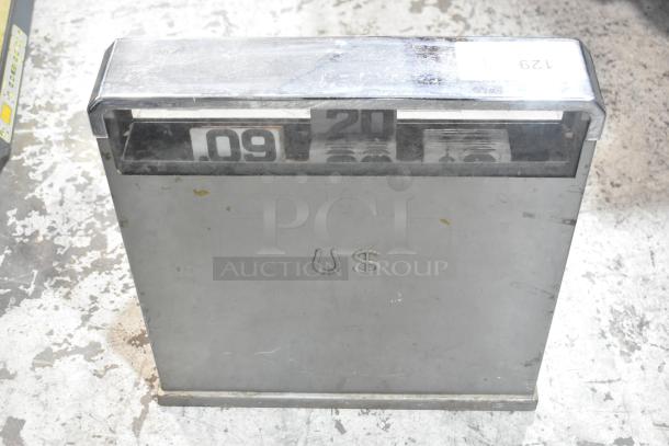 Metal countertop cash register with a chrome finish, visible numeric display, and "US" embossed on the front. Slightly worn condition.