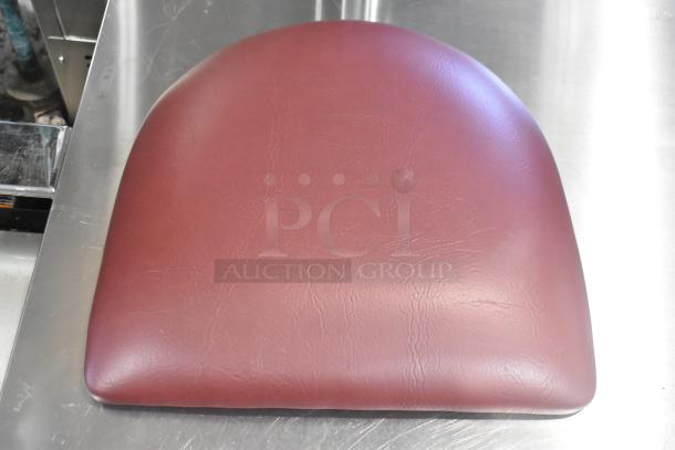 Maroon seat cushion, new condition, scratch and dent sale, smooth material, slightly rounded shape.