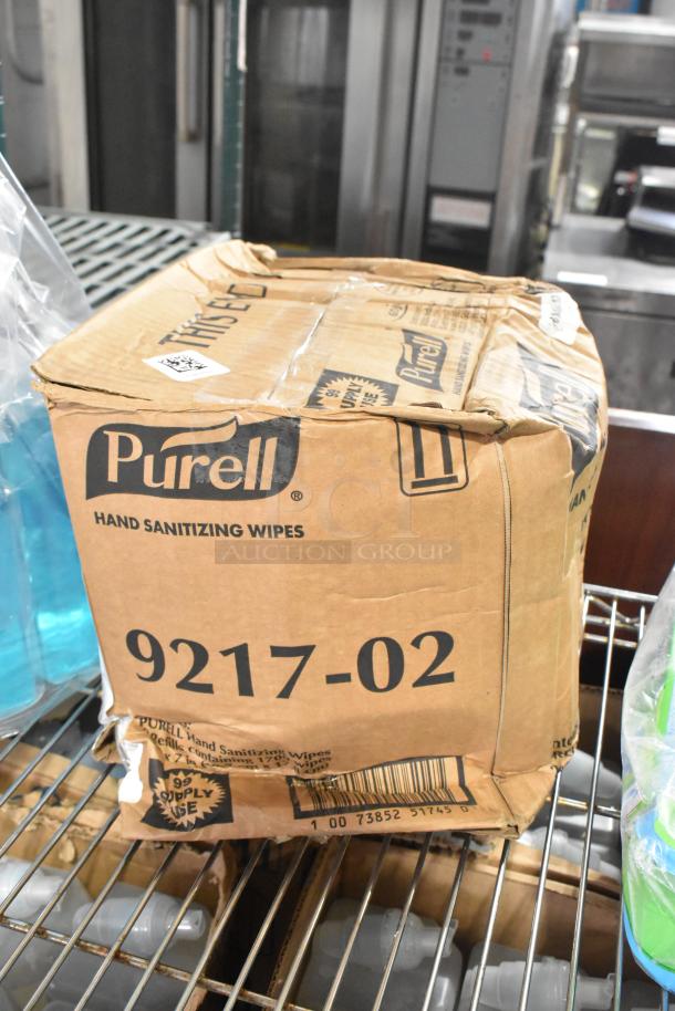 Cardboard box of Purell 9217-02 hand sanitizing wipes, slightly worn, on a metal shelf with additional cleaning supplies.