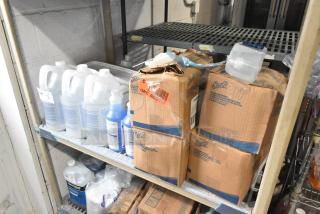 Tiered shelf with Scott Foam Skin Cleanser boxes and Diversey Oxivir Tb Virucide Sanitizer bottles, slightly worn.