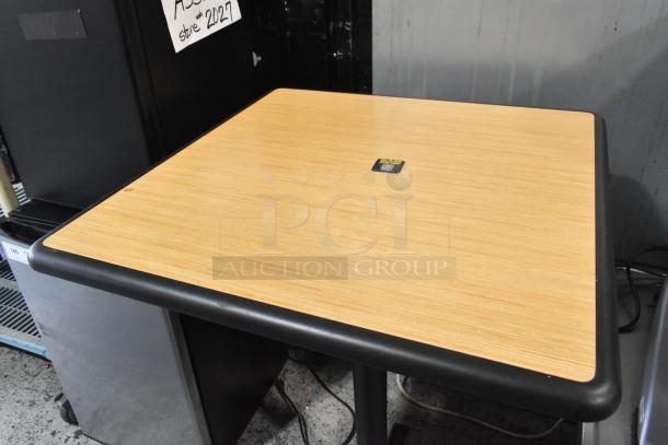 Square wood pattern bar height table on a black metal base, in good condition. There's a label in the center. Auction: 2 times bid.