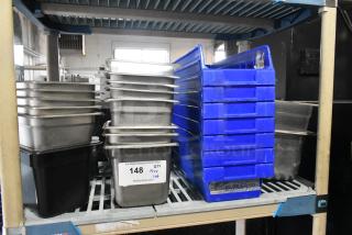 Tier lot of stainless steel drop-in bins and blue poly bins on a shelf. Tag reads "148, Qty Tier Lot, PCI Auctions."