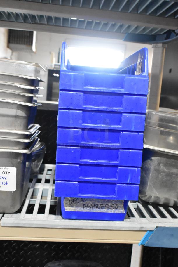 Tiered lot of stainless steel drop-in bins and blue poly bins labeled "Decaf Espresso" on metal shelves.