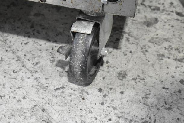 A close-up of a wheel on a Beverage Air UCR48AHC stainless steel cooler, showing wear and rough surface.