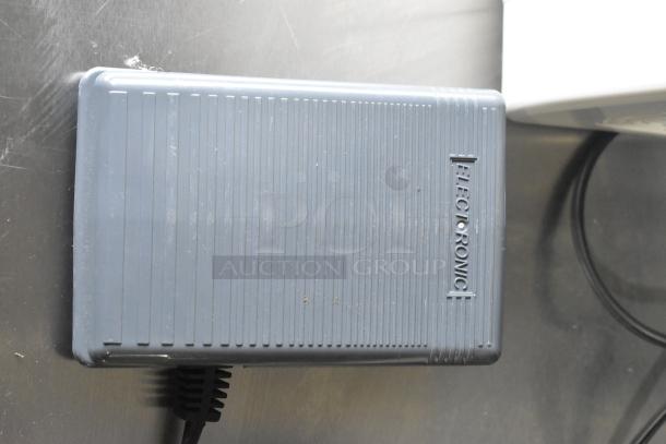 Gray foot pedal for Singer sewing machine, labeled "Electronic," with visible cord on a metal surface.