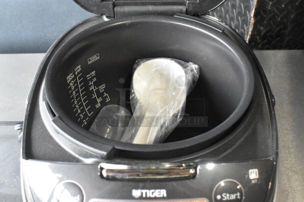 Tiger JKT-D18U rice cooker/warmer, lid open, inner markings visible. Lid does not close; includes accessories. 120V, 1-phase.