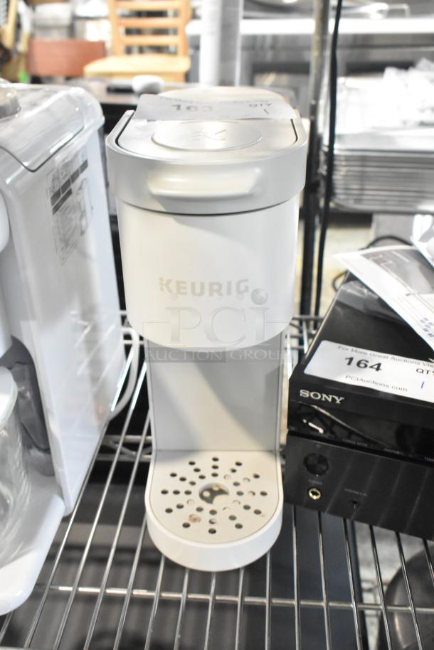 2024 Keurig Single Cup Coffee Maker, white, 120 volts, in good condition, on a metal shelf.