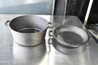 Box of cast iron pots and skillets, including a deep pot and a frying pan, both in excellent condition with dual handles.