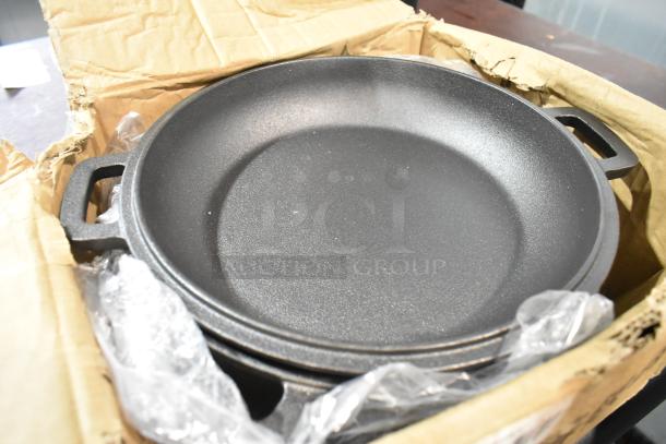 Box of cast iron pots/skillets, stacked, in original packaging. Slight wear on box edges. Durable kitchenware set.