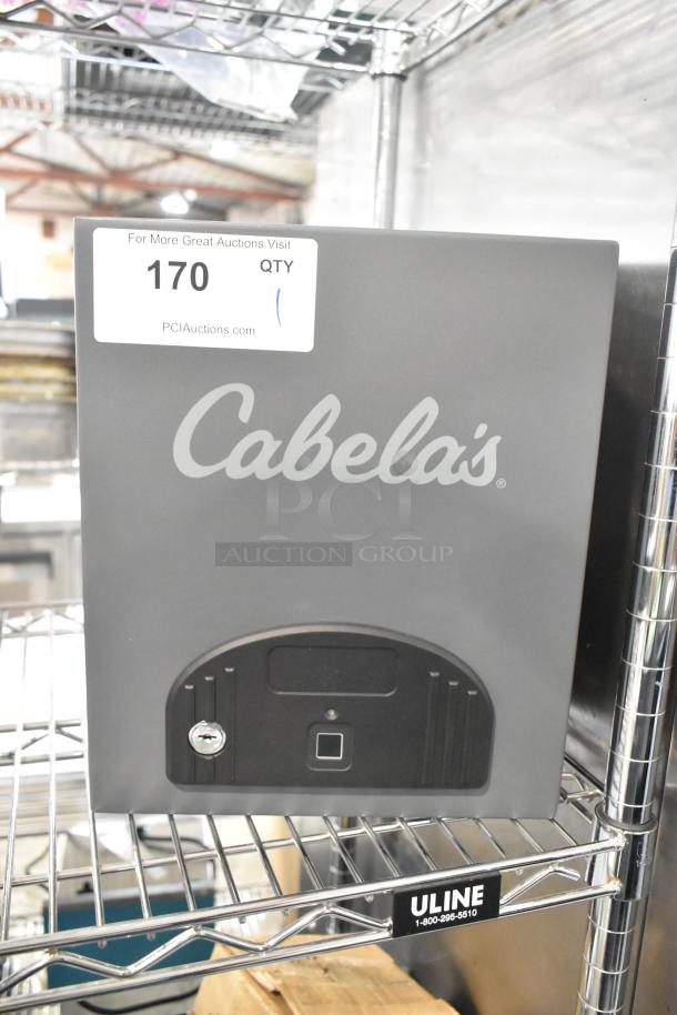 Cabela's gray metal safe, missing keys, with logo and lock visible, sturdy construction. Auction tag "170" attached.
