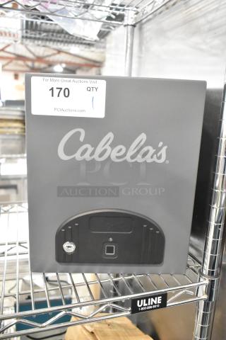 Cabela's gray metal safe, missing keys, with logo and lock visible, sturdy construction. Auction tag "170" attached.
