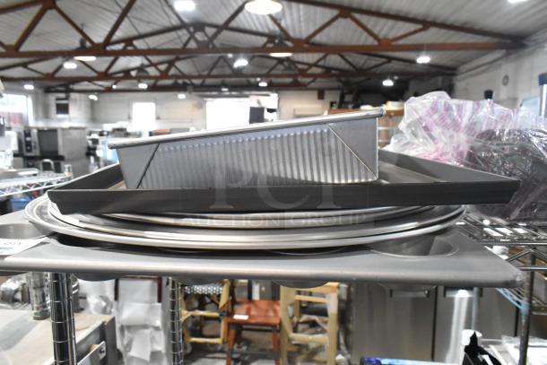 Assorted metal baking items, including muffin pan and round baking sheets, stacked in used condition.
