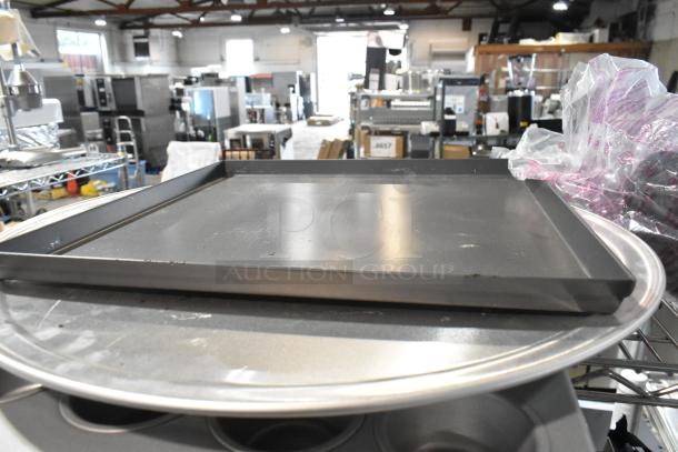 Lot of metal baking items including a muffin pan and round baking sheets in fair condition, suitable for kitchen use.