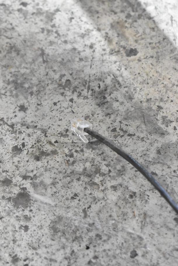 Close-up of the flavor dispenser's cable with a clear connector on a textured surface.