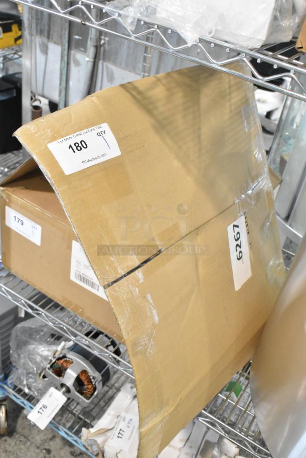 Cardboard box labeled "BRAND NEW SCRATCH AND DENT! Faucet w/ Handles" on a metal shelf. Labels show item number 180.