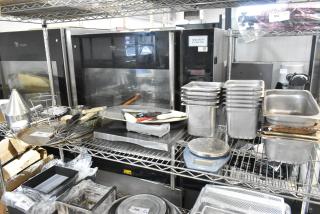 Auction lot featuring stainless steel drop-in bins, utensils, and kitchen tools on metal shelving. Includes Fri-Jado label ovens.