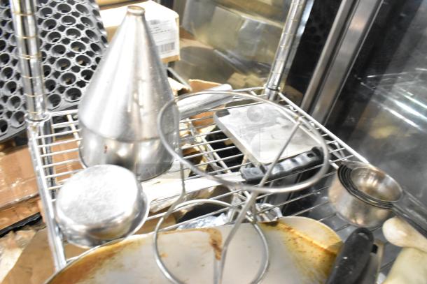 Stainless steel drop-in bins and various utensils on a metal rack, used condition, ideal for kitchen organization.