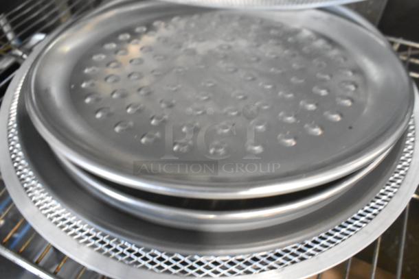 18 new metal mesh pans and round perforated baking sheets, slight scratches and dents, stacked on shelf.