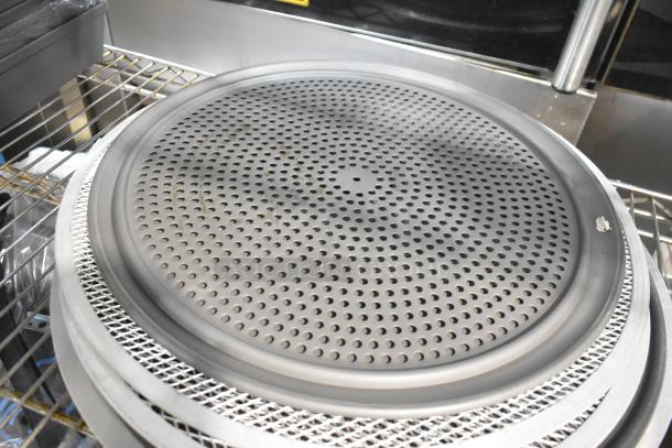 Alt text: Stack of perforated round baking sheets and metal mesh pans on a wire shelf, brand new scratch and dent condition.